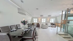 A modern dining area with a long table set for six, a chandelier, and a view of a living area with sofas and a coffee table. - CLASSIC LONDON ARCHITECTURE IN THE MOST DESIRABLE NEIGHBORHOODS—BAYSWATER (London)