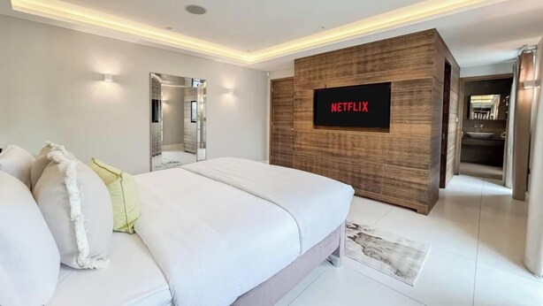 A modern bedroom with a large bed, a wall-mounted TV, and a wooden accent wall. - CLASSIC LONDON ARCHITECTURE IN THE MOST DESIRABLE NEIGHBORHOODS—BAYSWATER (London)