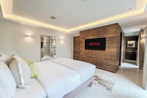 A modern bedroom with a large bed, a wall-mounted TV, and a wooden accent wall.