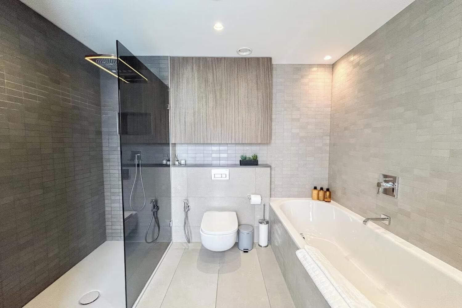 Een moderne badkamer met een douchecabine van glas, een vrijstaand bad en een toilet.