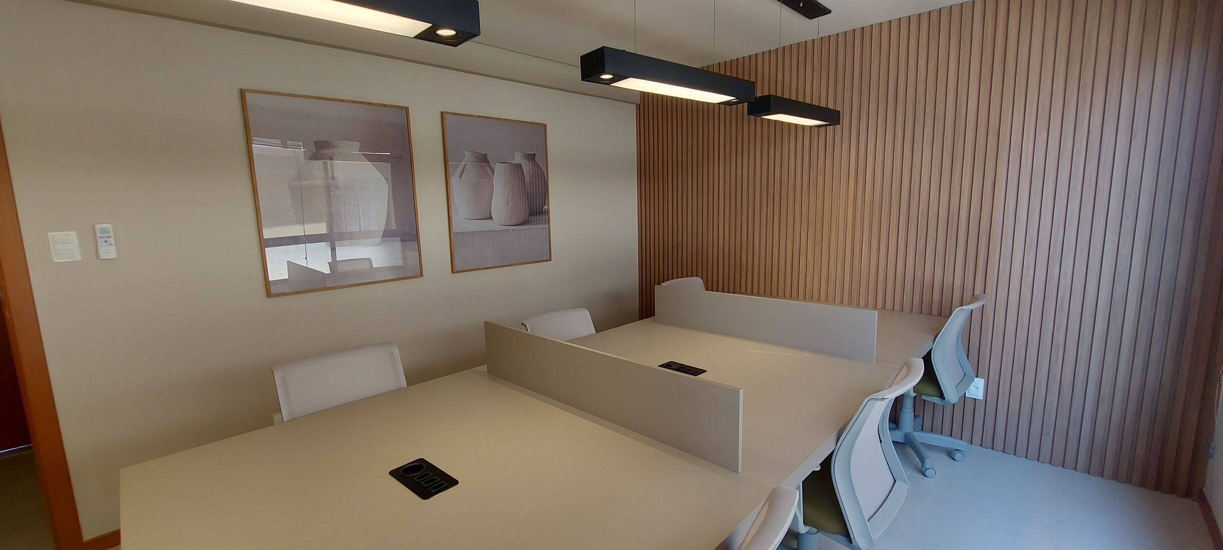 Une chambre d’hôtel avec un mur lambrissé en bois, deux lits avec du linge de lit blanc et deux tableaux encadrés accrochés au mur.