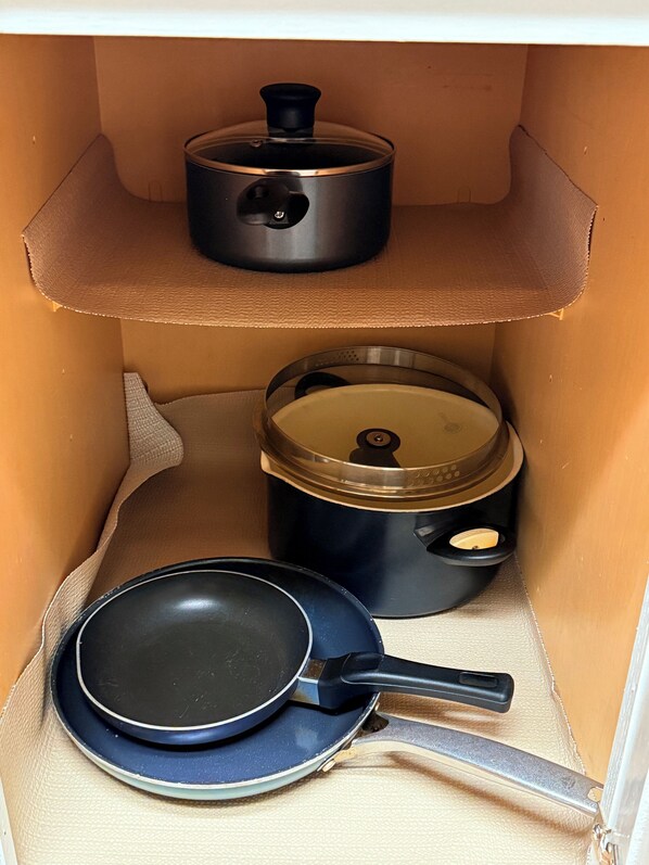 Uma cozinha com fogão, uma frigideira e uma panela em uma prateleira.