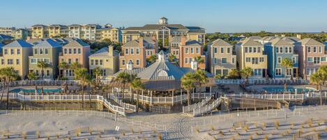 A beachfront hotel with multiple buildings, a central pool area, and a beach with sun loungers.