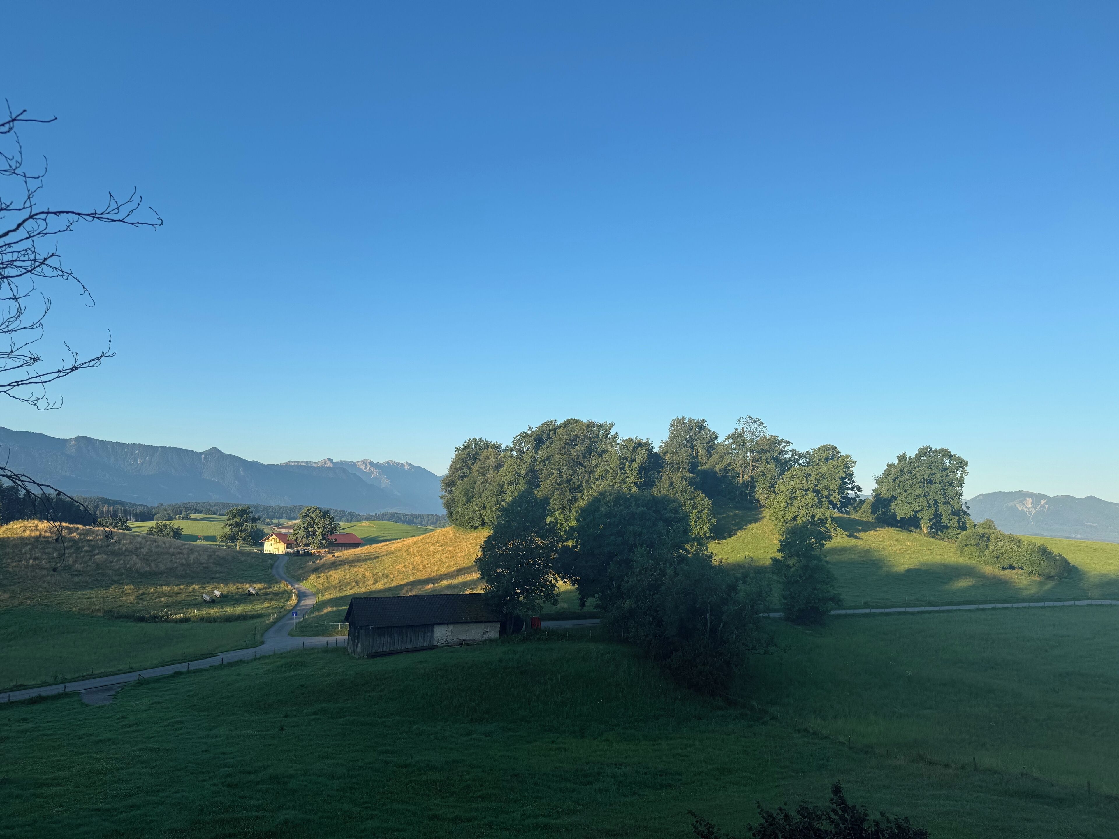 Ländliche Landschaft mit Scheune, Straße und fernen Bergen.