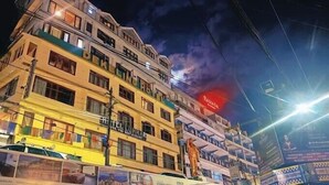 Un hôtel à plusieurs étages, doté de balcons et d’une grande enseigne rouge bien visible sur le dernier étage.