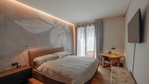 A modern hotel room with a large bed, a desk, and a TV. - Charming Garden Hideaway in Como by Rent all Como (Como)
