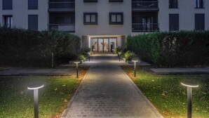 A modern building with a central entrance, surrounded by well-maintained hedges and a paved pathway leading to the entrance. - Charming Garden Hideaway in Como by Rent all Como (Como)