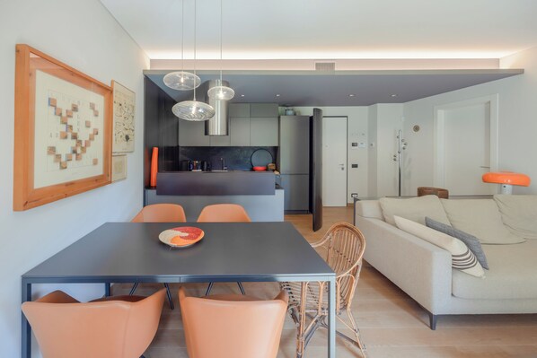 Un salon moderne comprenant un canapé, une table à manger et des chaises. Il y a également un coin cuisine avec un réfrigérateur et un évier.