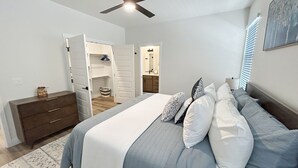 Ein Schlafzimmer mit Bett, Schminktisch, Deckenventilator und begehbarem Kleiderschrank.