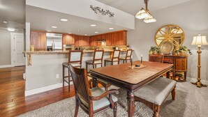 A spacious dining area with a wooden table and chairs, a kitchen in the background, and a decorative mirror on the wall. - Spacious Elegance-Kirkwood-Timber Ridge 3 Bedroom 3 Residence (Kirkwood)