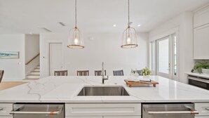 Una cocina moderna con una isla grande, electrodomésticos de acero inoxidable e iluminación colgante.