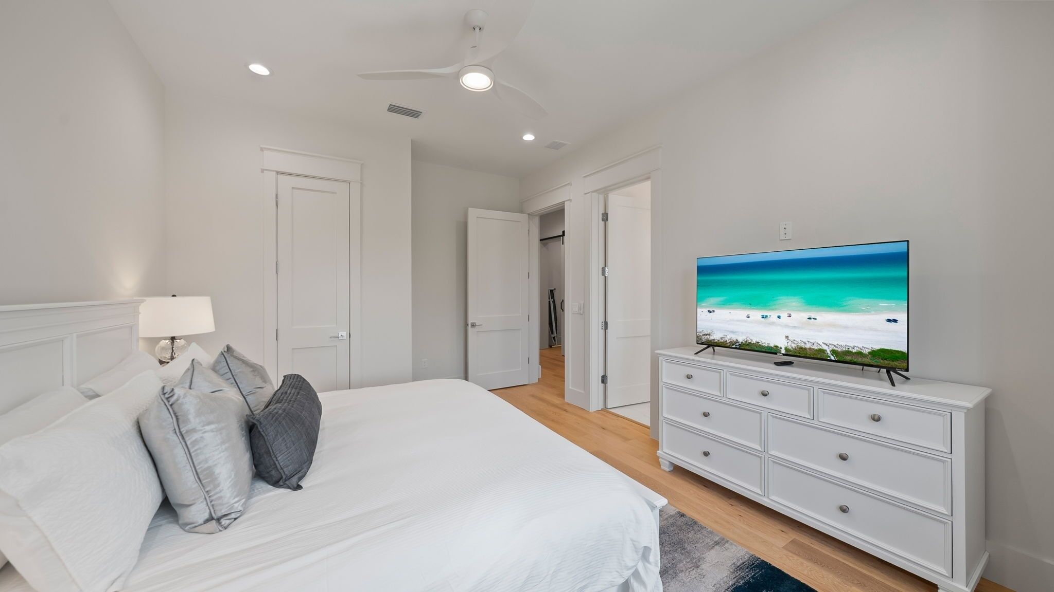 Ein Schlafzimmer mit einem Bett, einem Fernseher auf einer Kommode und einem Deckenventilator.