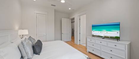 Ein Schlafzimmer mit einem Bett, einem Fernseher auf einer Kommode und einem Deckenventilator.