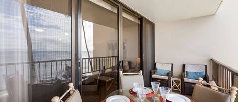 Un coin repas avec une table en verre pour quatre personnes, entourée de chaises en osier.