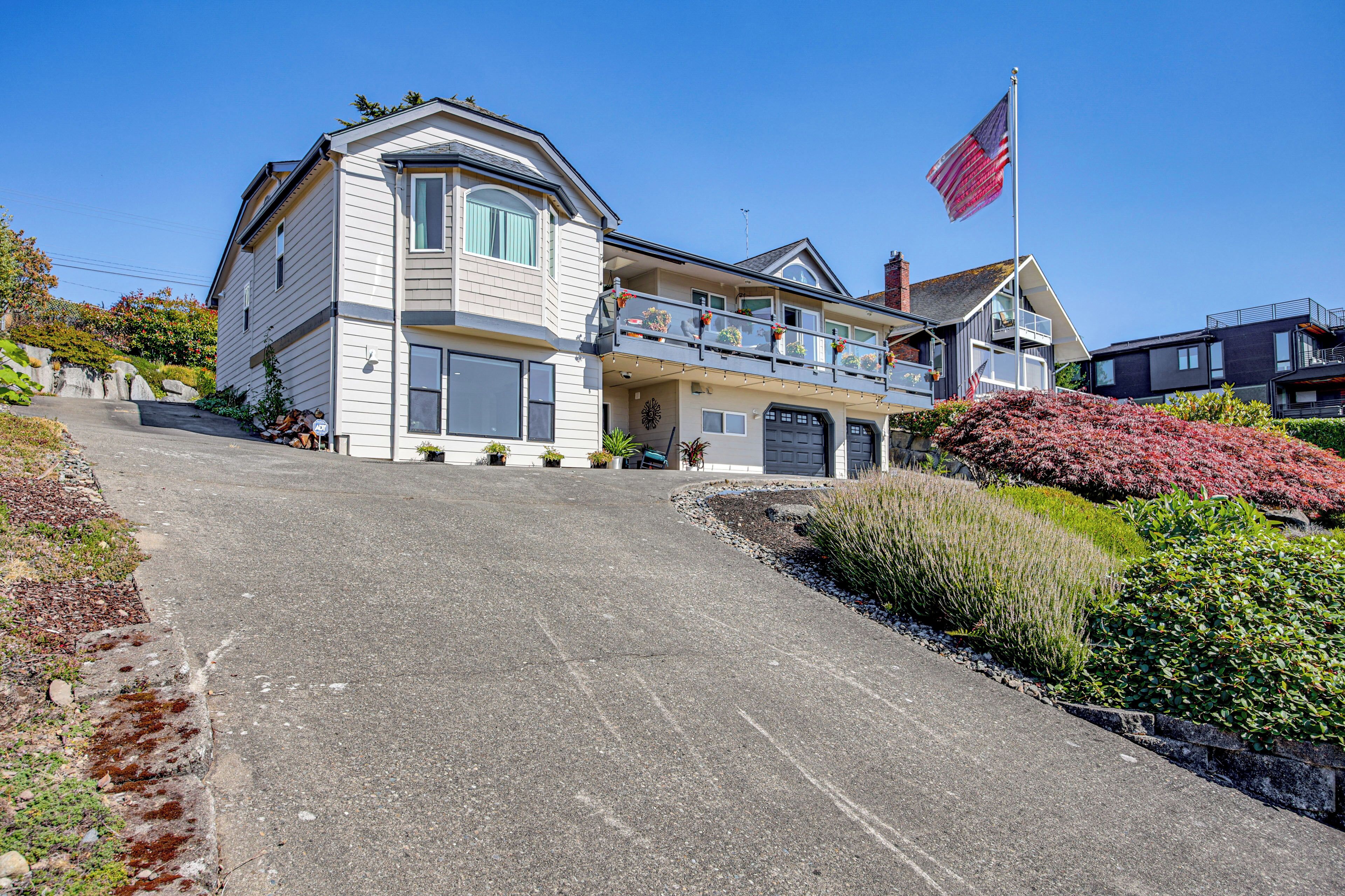 A large, two-story house with a balcony, a garage, and a flag.