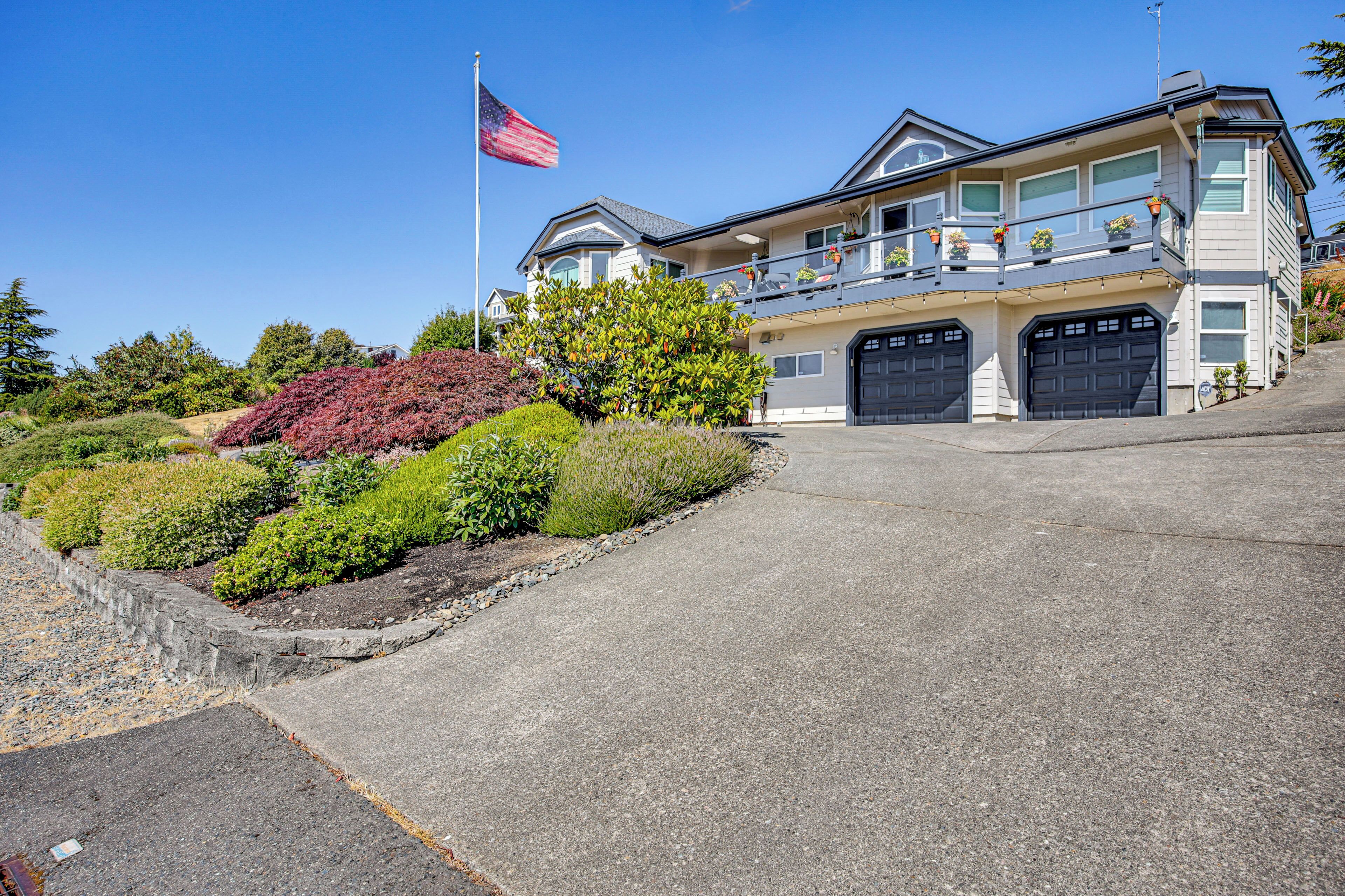 A two-story house with a balcony, a garage, and a flag.