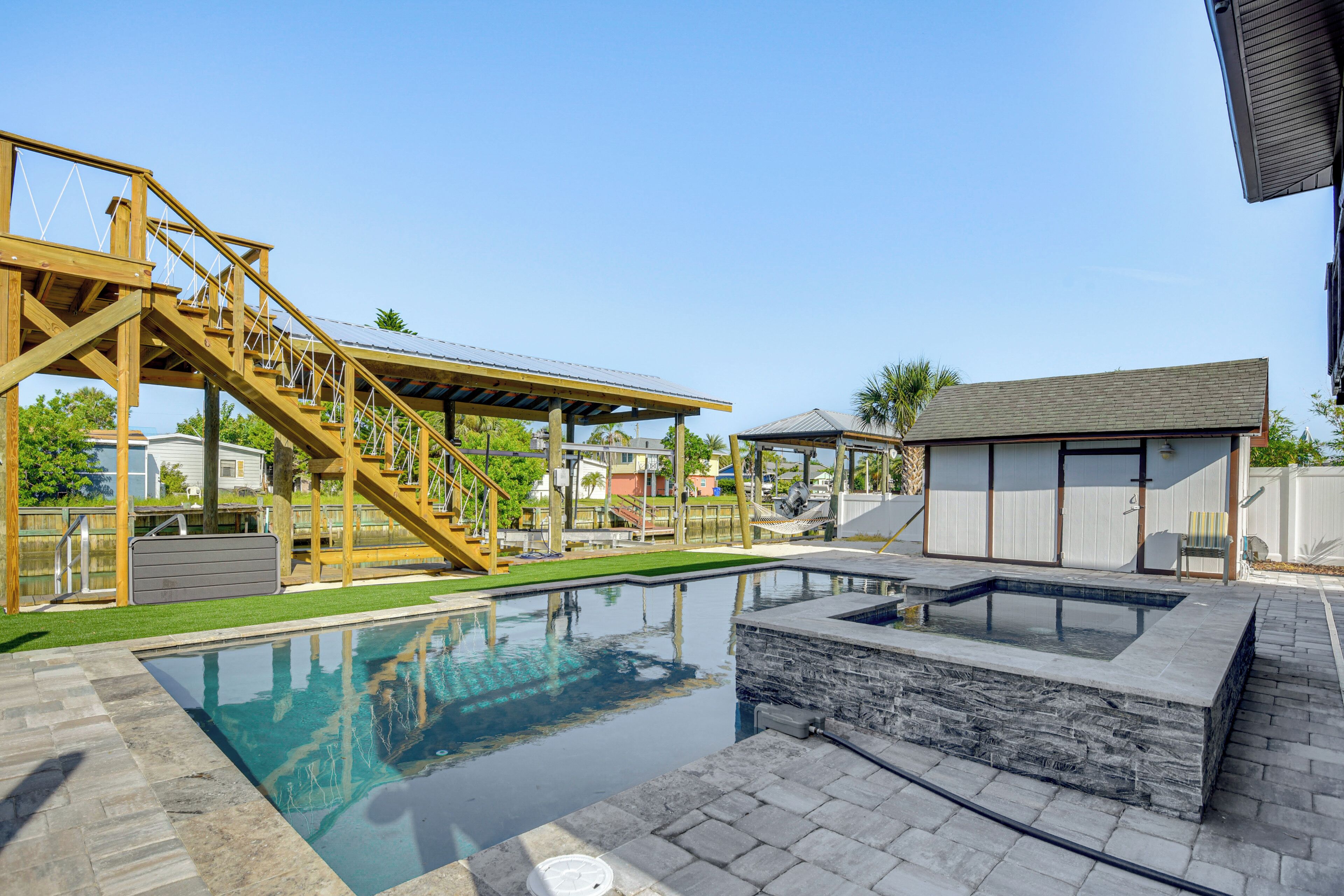 A swimming pool with a wooden deck and a small building with a roof.