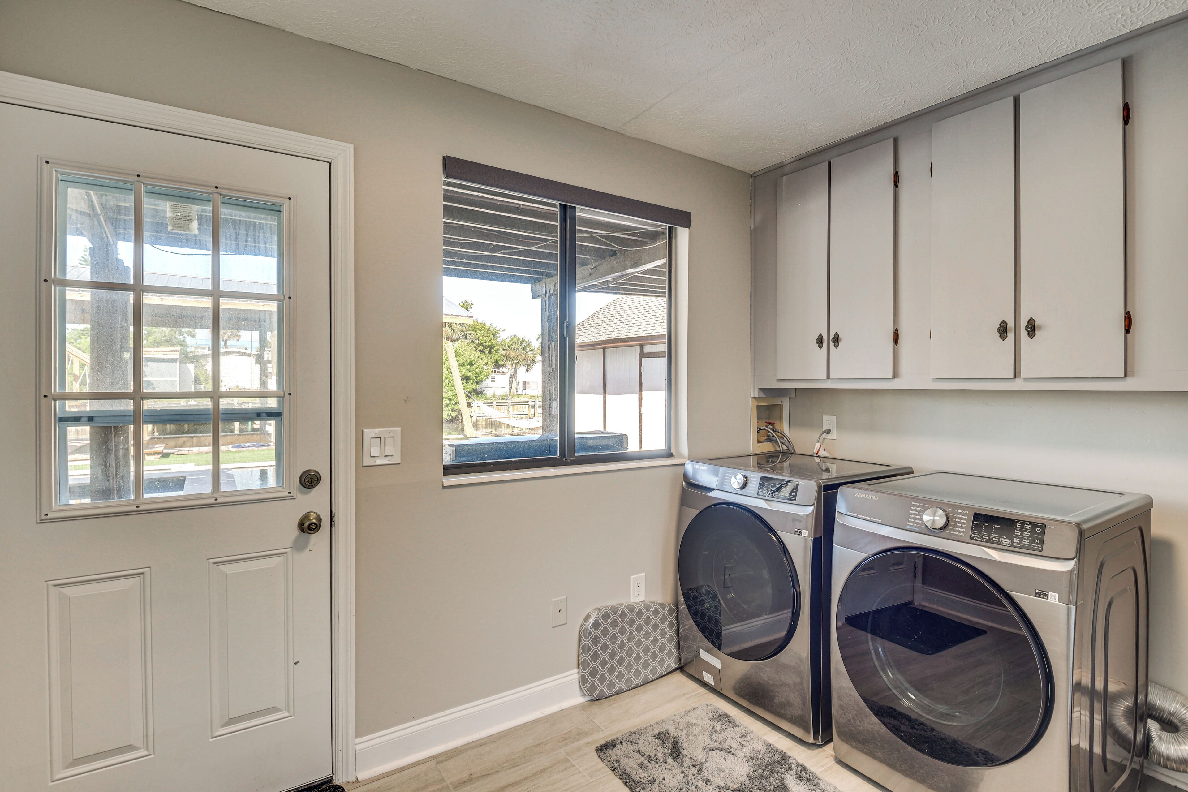 A laundry room with two washing machines, a drying rack, and a window providing natural light.