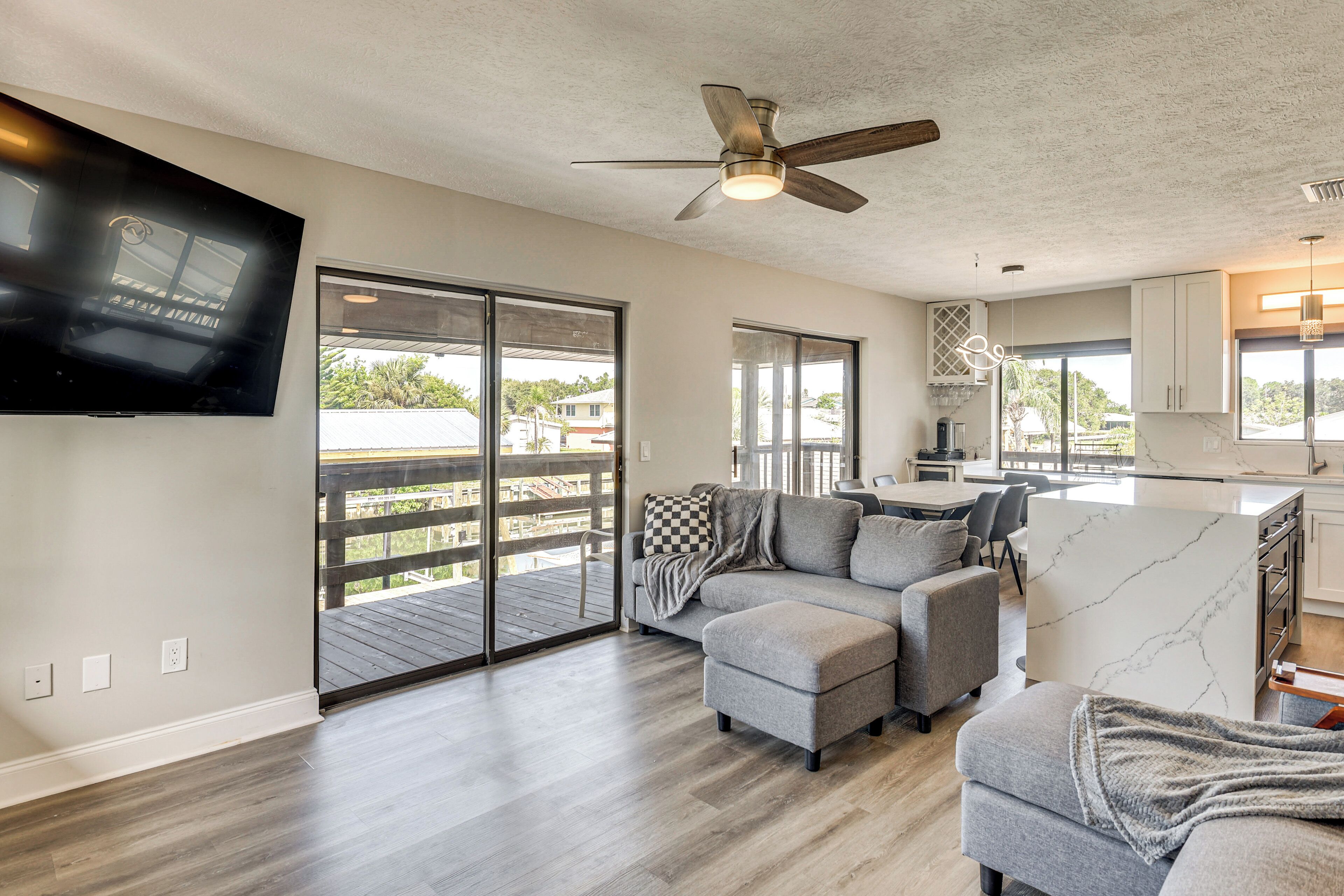 A spacious living area with a grey sofa, ottoman, and a ceiling fan.