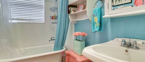 A bathroom with a bathtub, toilet, sink, and a shower curtain.