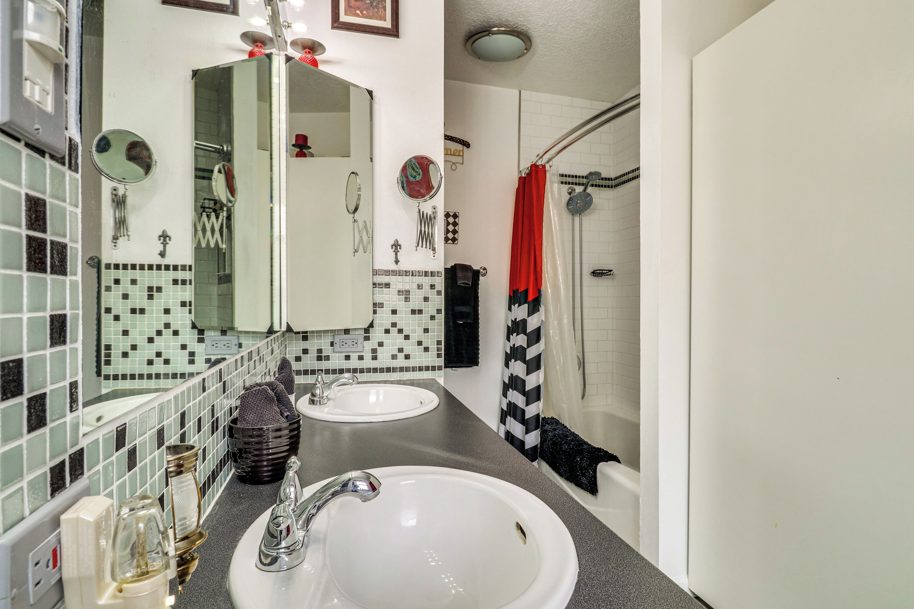 A bathroom with two sinks, a mirror, and a shower area with a red curtain.