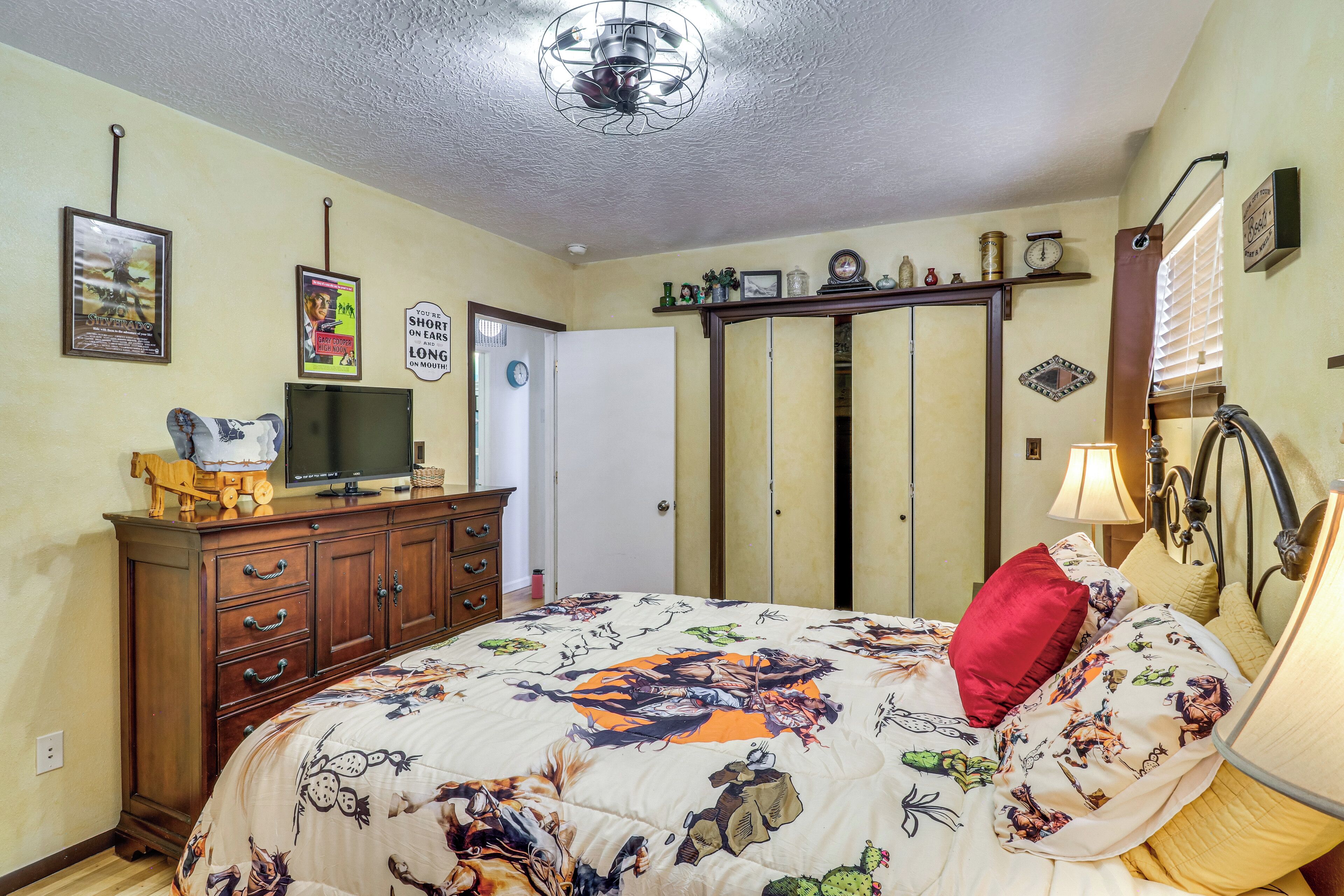 Una camera da letto con un letto, una cassettiera, una televisione e diverse decorazioni a parete.