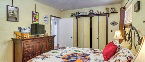 Una camera da letto con un letto, una cassettiera, una televisione e diverse decorazioni a parete.