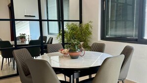 A modern dining area with a round table, six chairs, and a potted plant. - Ace Homes Bubga 3BR (Kampala)