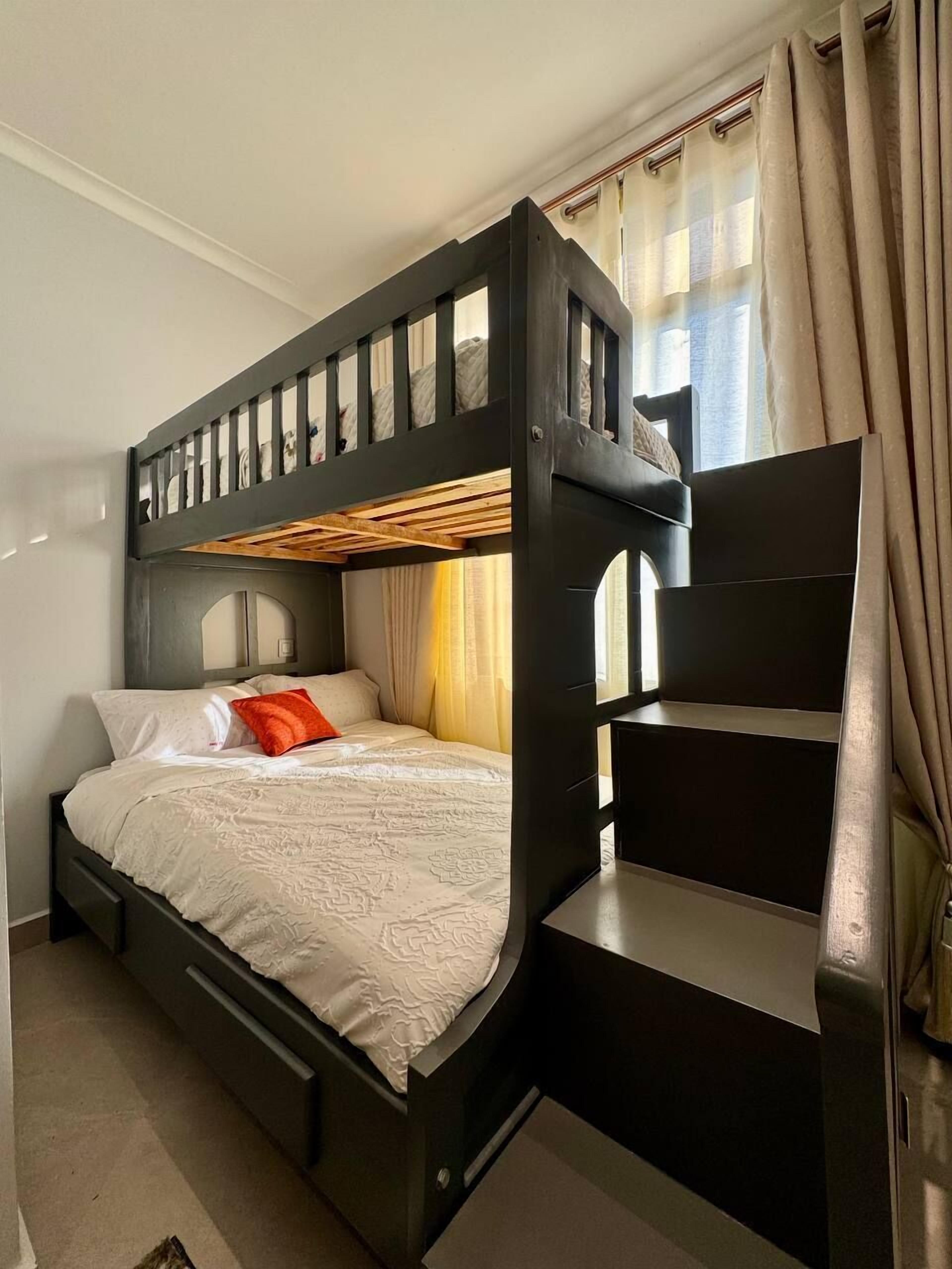 Un lit superposé avec une structure en bois et un lit inférieur recouvert d’une courtepointe blanche.