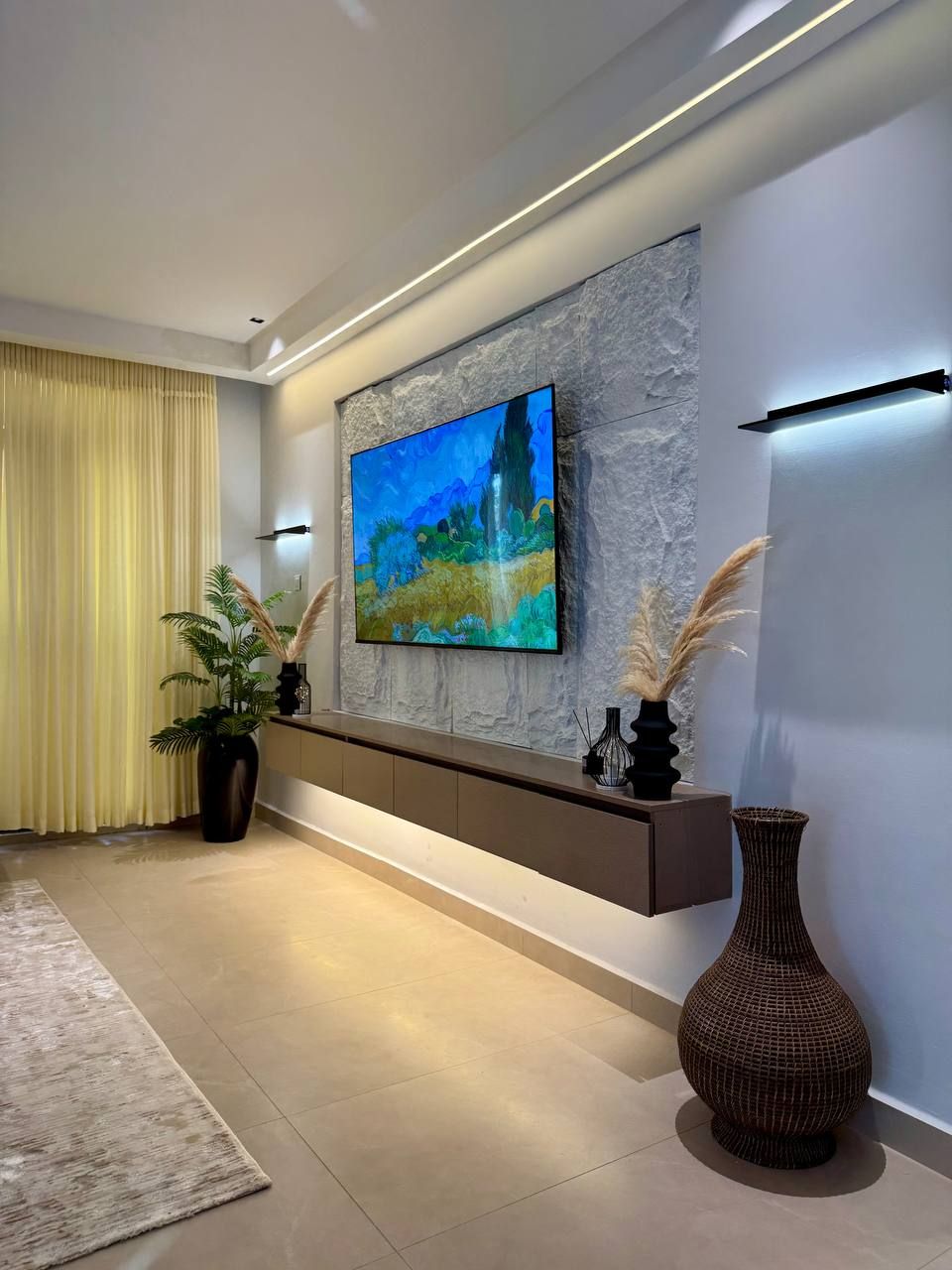 Een moderne woonkamer met een flatscreen televisie aan een gestructureerde muur, een donker houten console en decoratieve vazen.