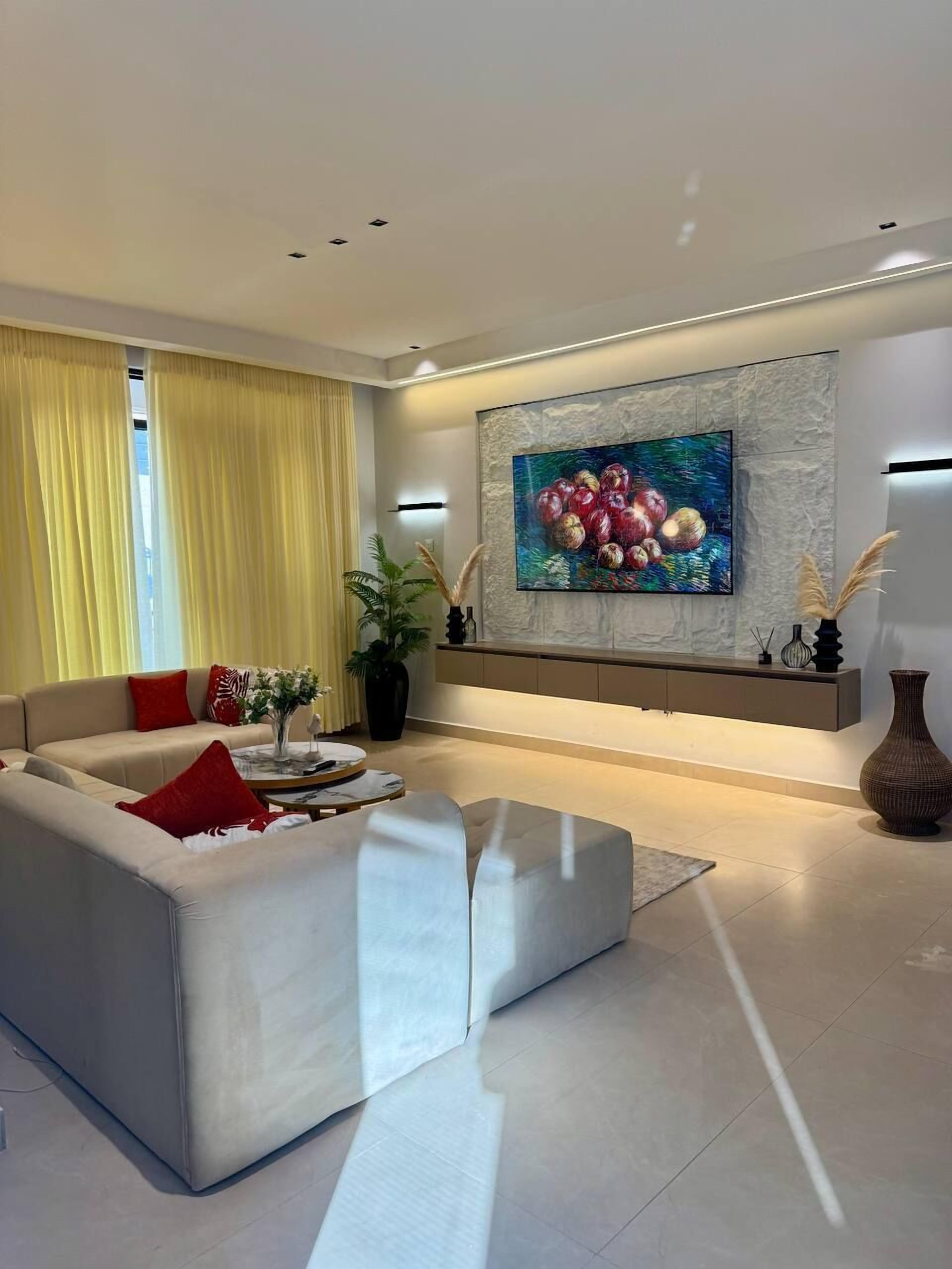 A modern living room with a sofa, a coffee table, and a large painting on the wall.