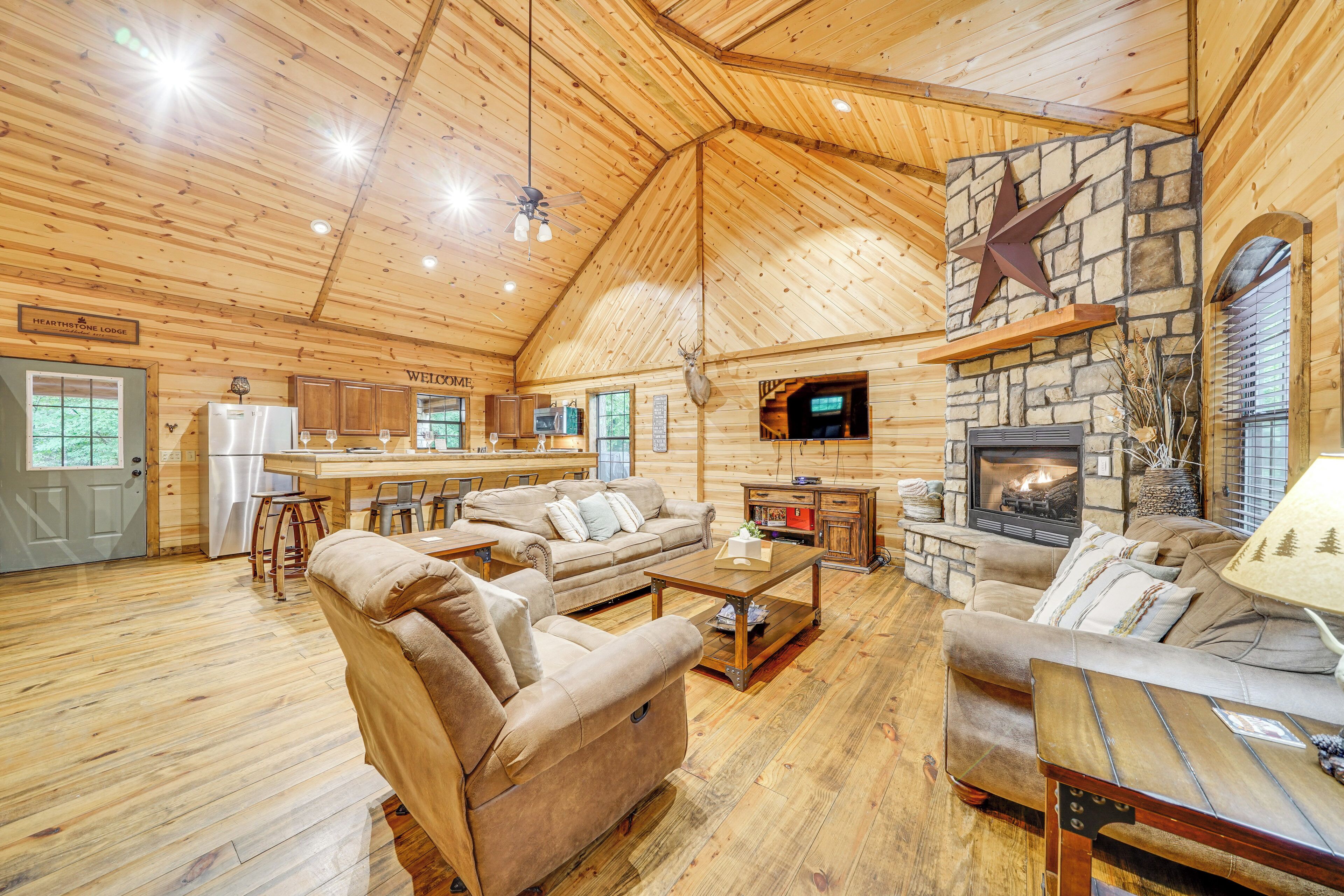 Een ruim interieur van een lodge met een stenen openhaard, houten plafond en een gezellige zithoek.
