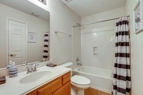 Un baño con lavamanos, espejo y retrete blancos.