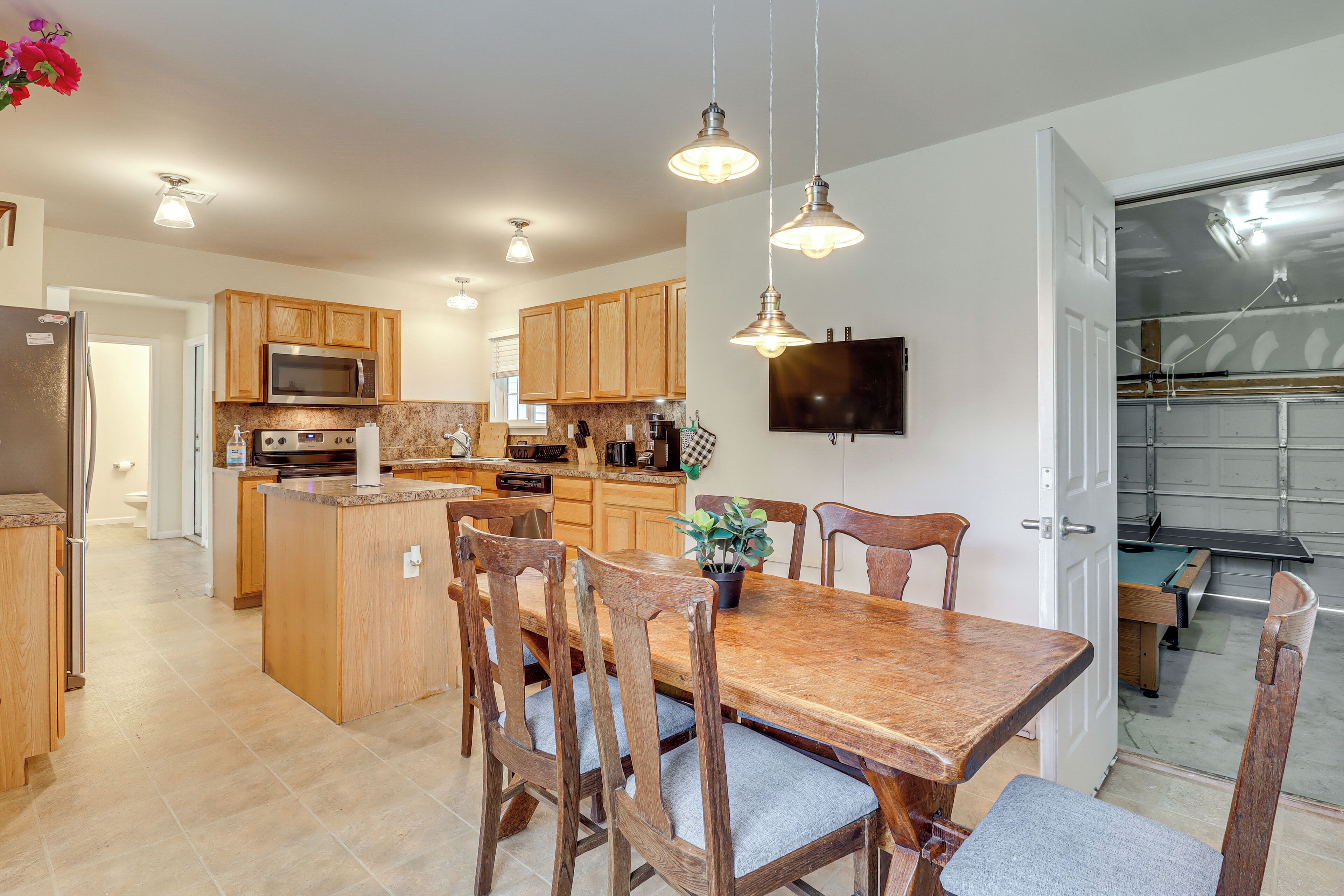 Una cocina moderna con armarios de madera, una isla central y una zona de comedor con mesa y sillas de madera.