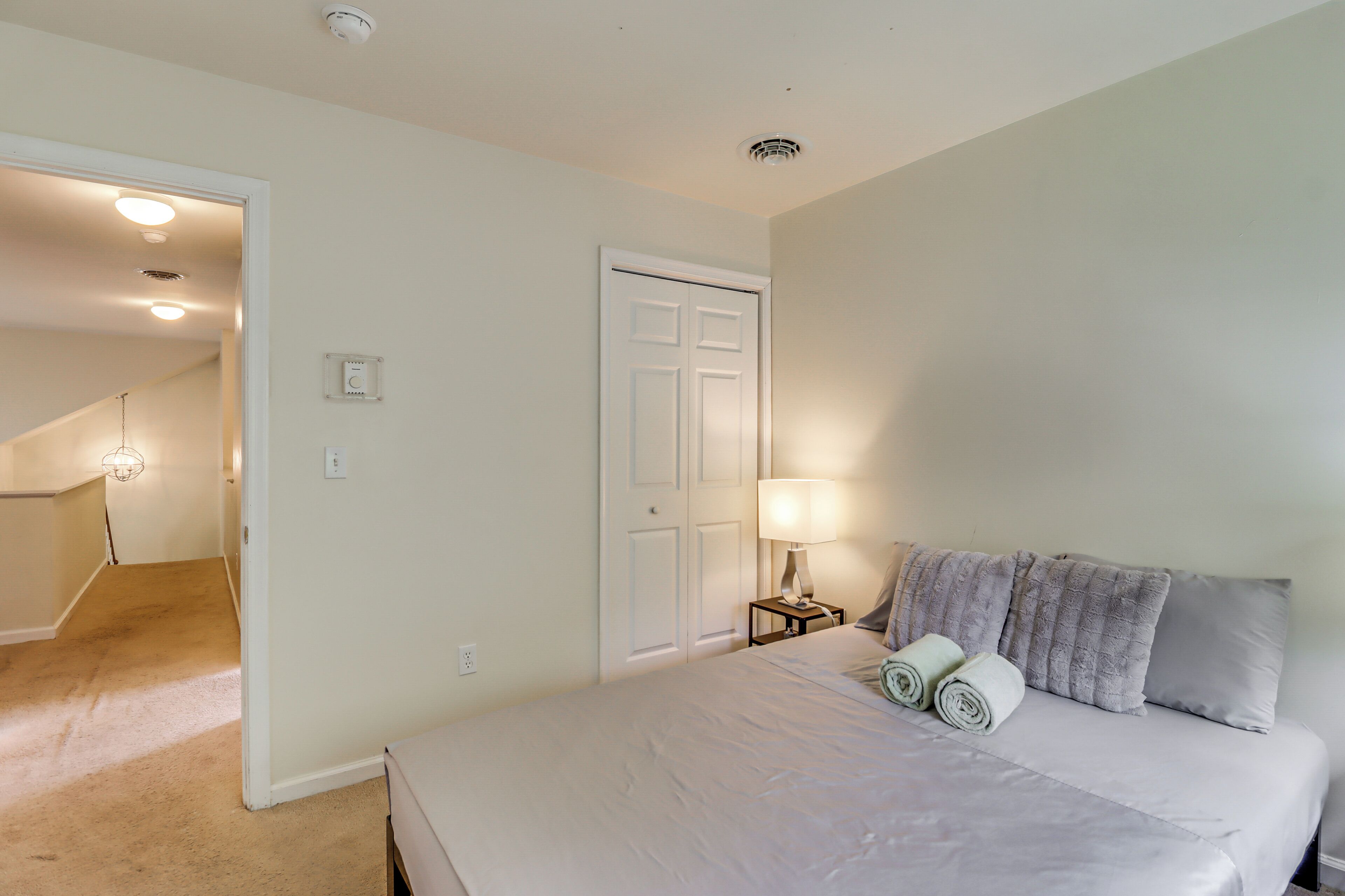 A bedroom with a bed, a nightstand, a lamp, and a door.