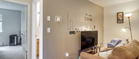 A living room with a beige wall, a brown couch, a TV, and a lamp.
