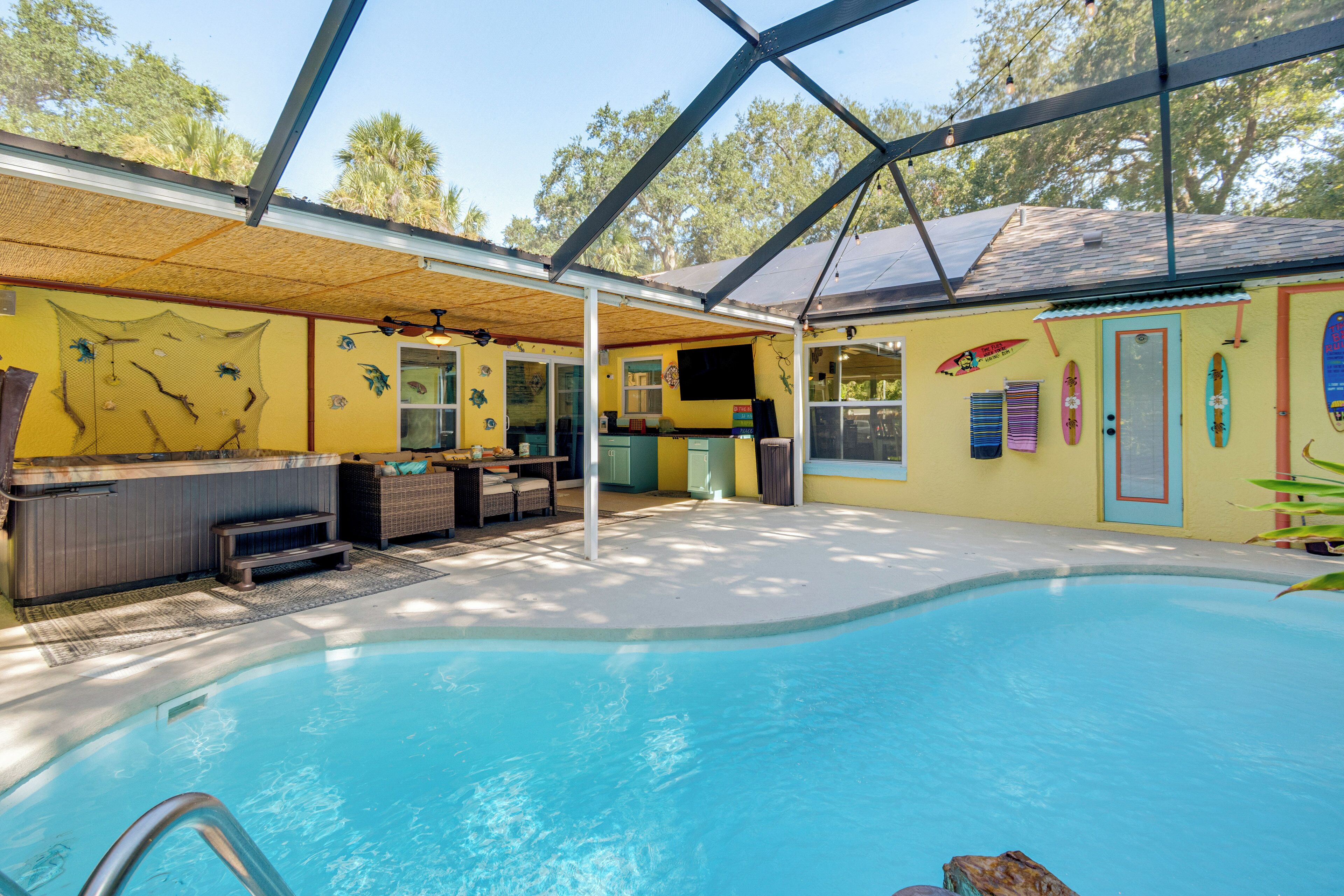A pool area with a covered seating area, a hot tub, and a small bar.