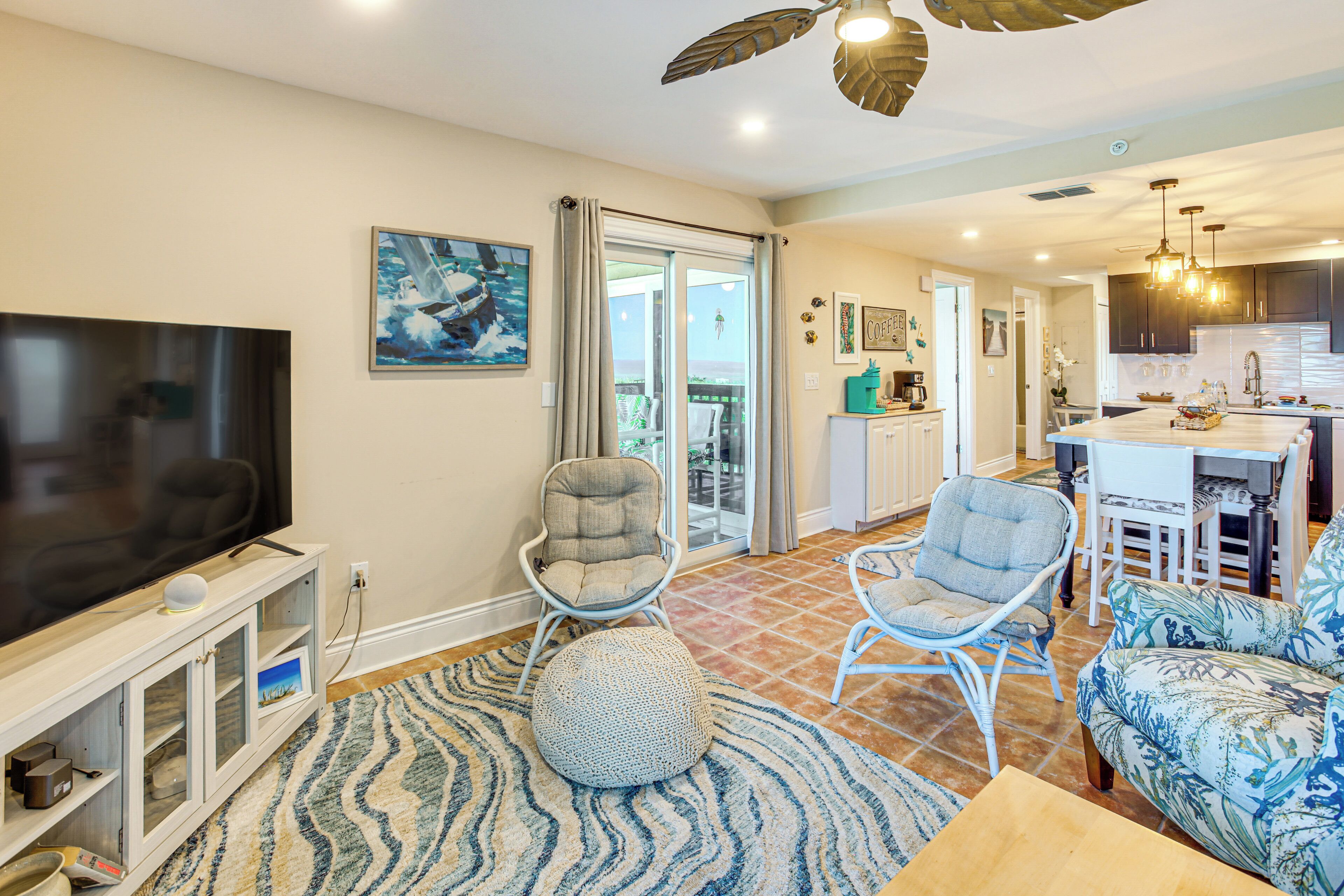 A living room with a TV, seating, and a kitchen area.