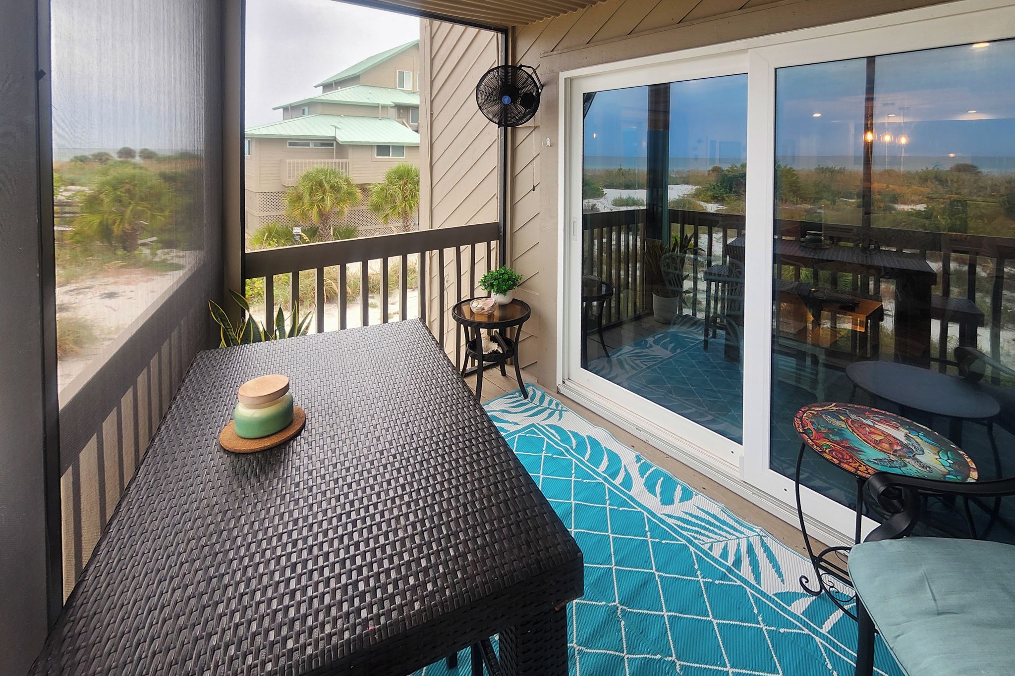 A covered outdoor area with a table, chairs, and a fan.