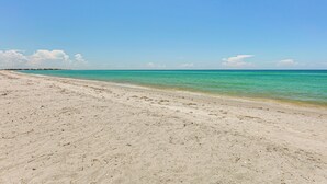 Une plage à l’eau turquoise et limpide, bordée d’un rivage sablonneux.