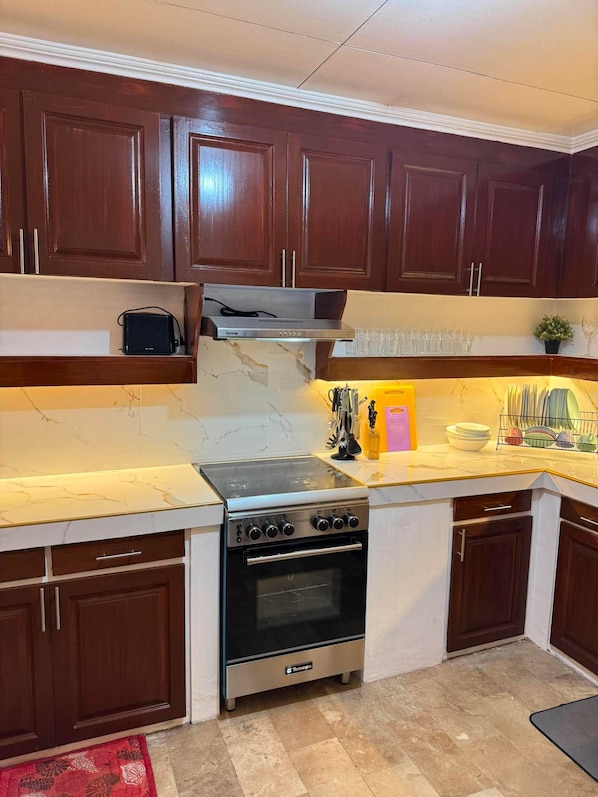 A kitchen with dark wooden cabinets, a stainless steel stove, and a marble countertop.
