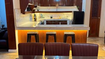 A modern kitchen with a central island, bar stools, and a dining table.