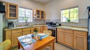 A compact kitchen with wooden cabinets, a dining table with chairs, a microwave, an oven, and a coffee maker. - Fish, Raft & Hike: Southwest OR Couples Retreat! (Trail)