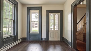 A spacious room with hardwood flooring, a dark blue door, and a white door with a window. - Walk to Dtwn Bath: Apt Near Keuka Lake & Wine Trl (Bath)