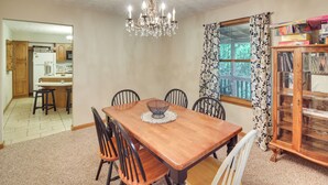 A dining room with a wooden table, chairs, a chandelier, and a cabinet with glass doors. - Family Home w/ Game Room! 1 Mi to Dale Hollow Lake (Burkesville)