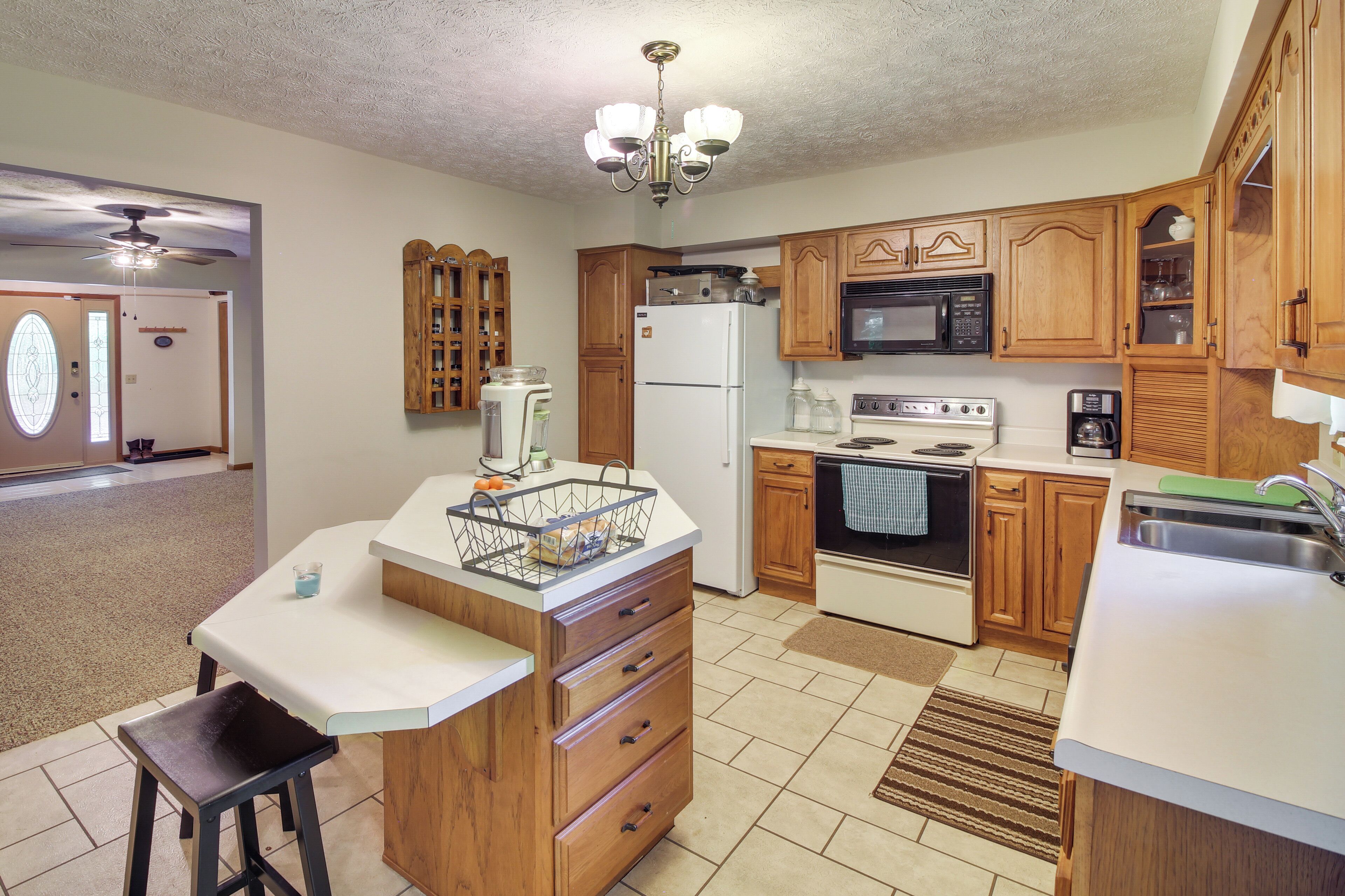 A kitchen with wooden cabinets, a refrigerator, microwave, stove, and a sink.