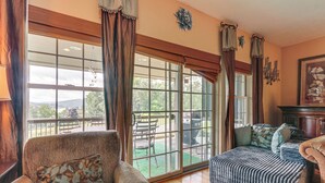 A spacious room with large windows, a sofa, a bench, and a dining area visible through the glass doors. - 1 Mi to Wisp Resort: Hot Tub Haven in Mchenry! (McHenry)