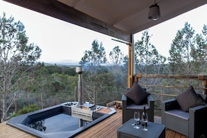 A hot tub on a wooden deck with wicker furniture and a view of trees and mountains. - Coopers Highlands  (Jeffreys Bay)