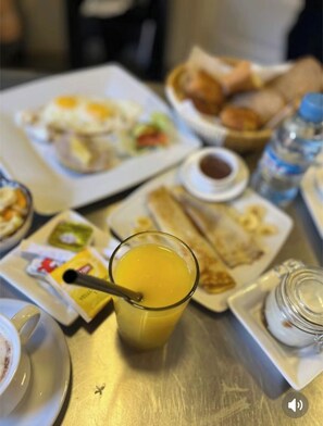 A breakfast setting with various dishes, including eggs, toast, and a glass of orange juice.