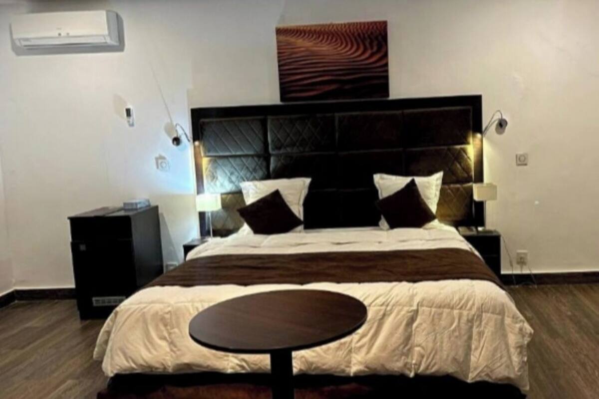 Ein Hotelzimmer mit einem großen Bett, Nachttischen, einem runden Tisch und einer Wandklimaanlage.